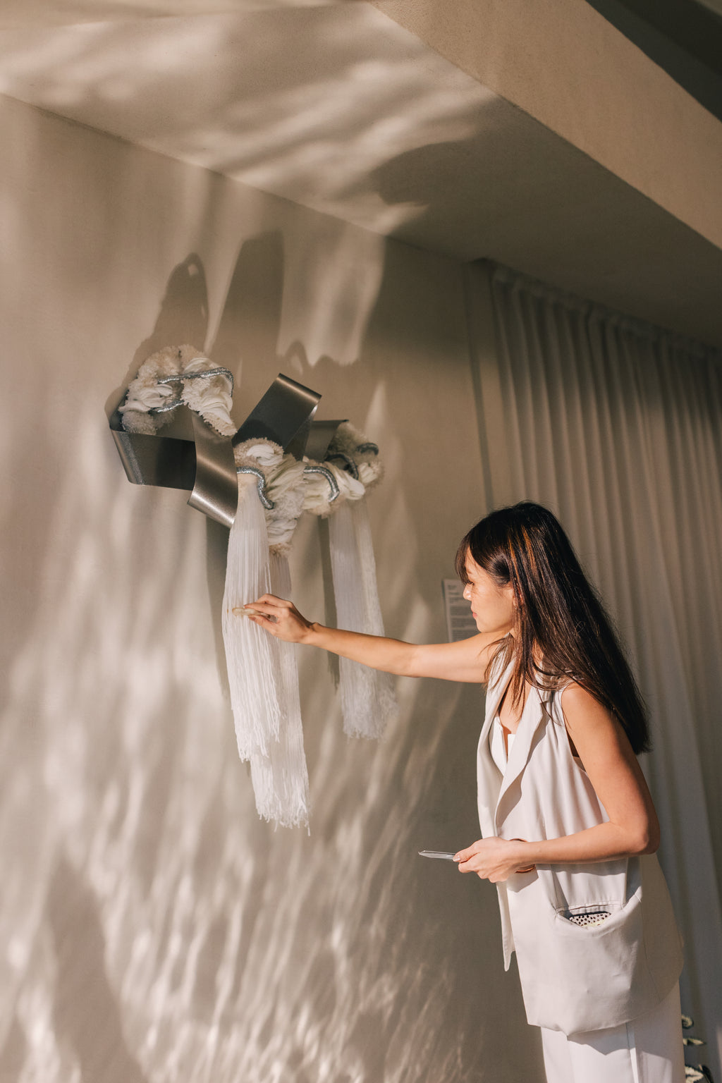 The Morning Glow fibre art displayed on a pale wall, its warm tones casting soft shadows that evoke dawn’s gentle light.