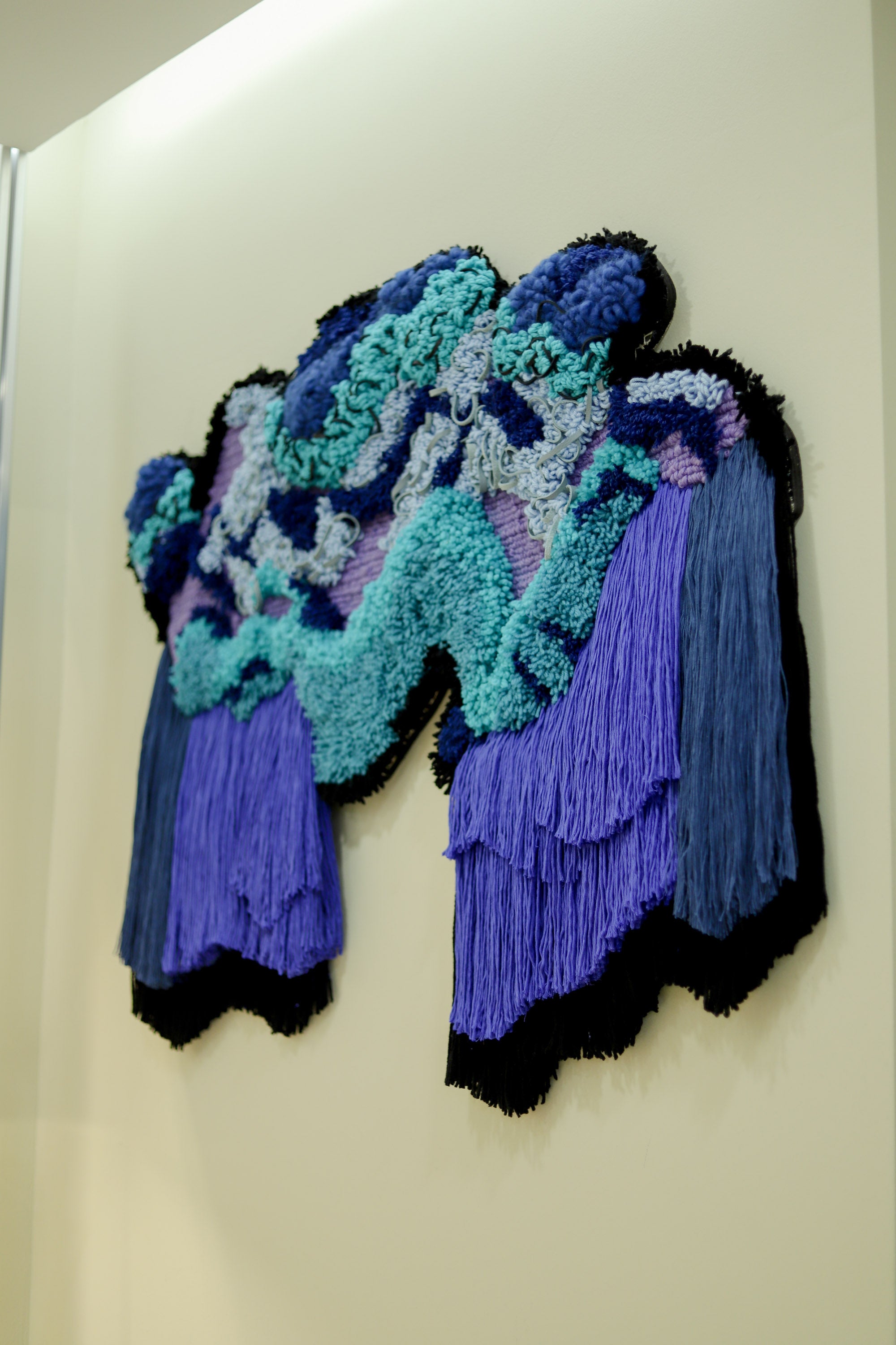 Handcrafted ‘Cascade’ textile piece: soft yarns in cool tones drape and tumble, evoking the calm movement of water over rocks.