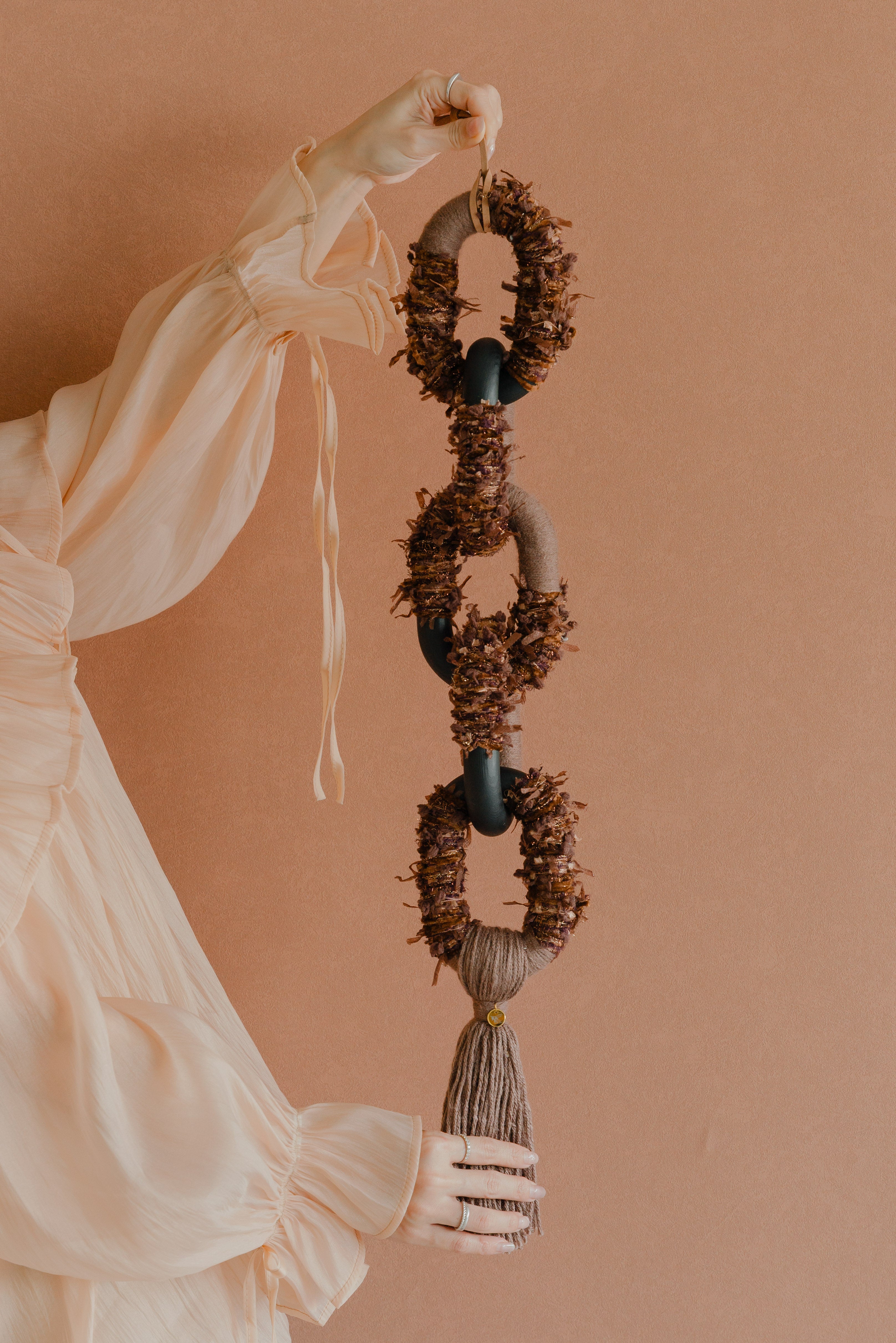 Passing By Blooms Mocha fibre wall art — warm mocha and cream yarn woven with leather accents, evoking a soft, trailing floral field.