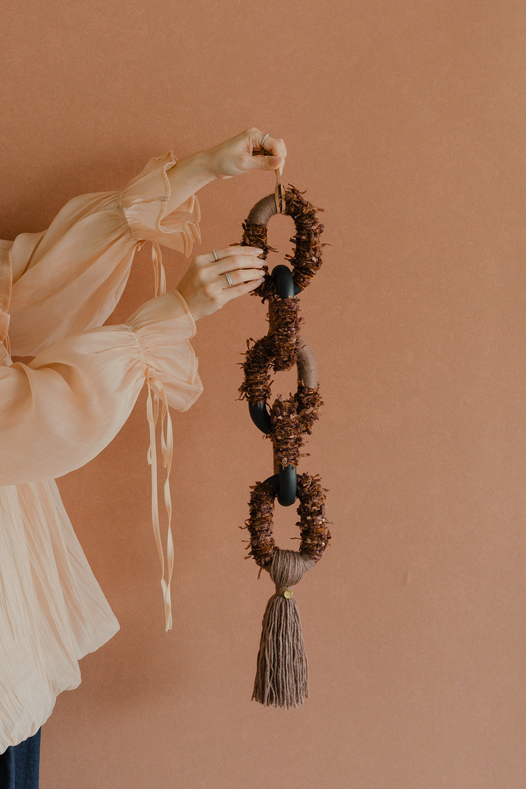 Bespoke textile art ‘Passing By Blooms Mocha’: woven yarn in soft brown and ivory shades, interlaced with leather trimmings for a delicate floral impression.