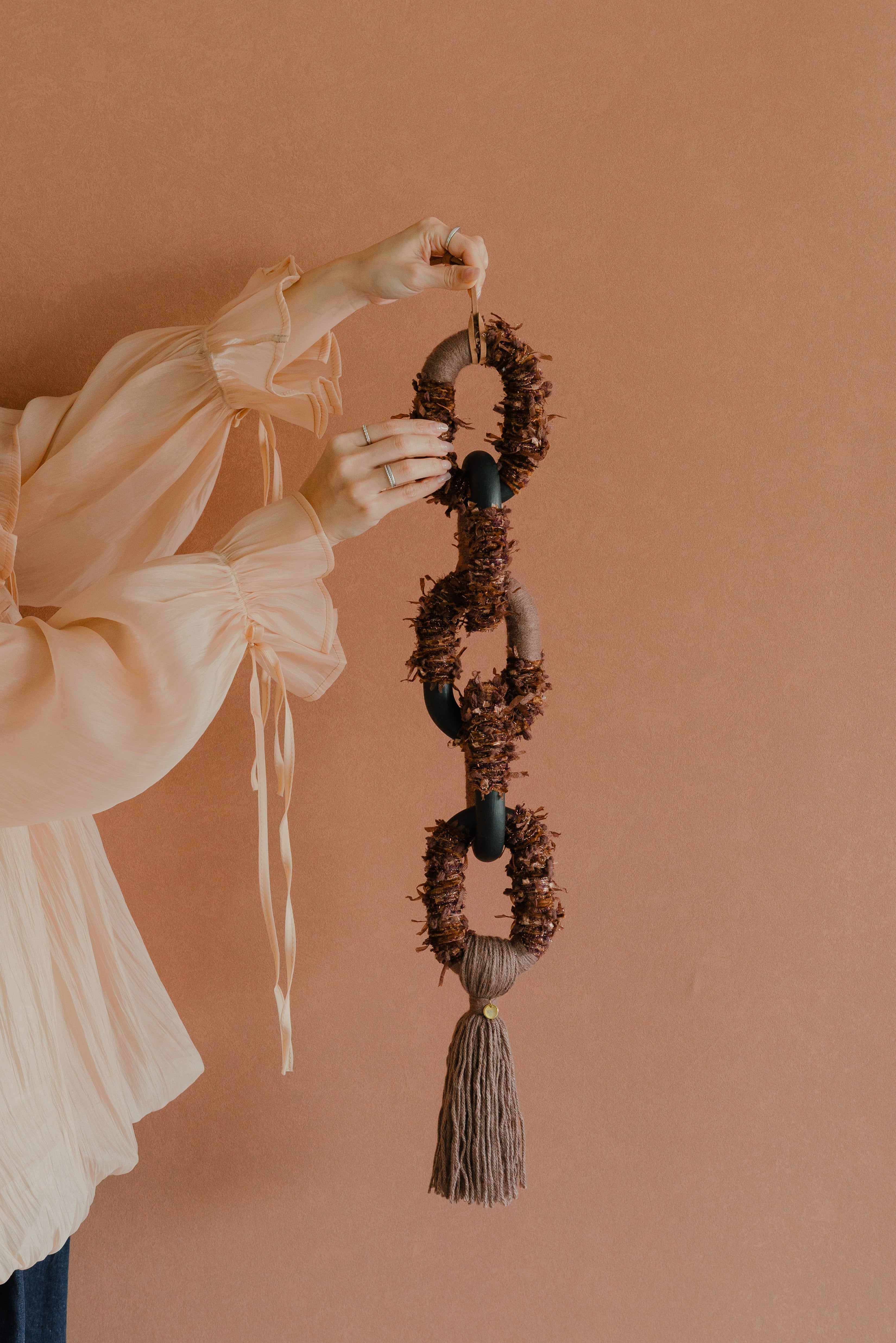 Bespoke textile art ‘Passing By Blooms Mocha’: woven yarn in soft brown and ivory shades, interlaced with leather trimmings for a delicate floral impression.