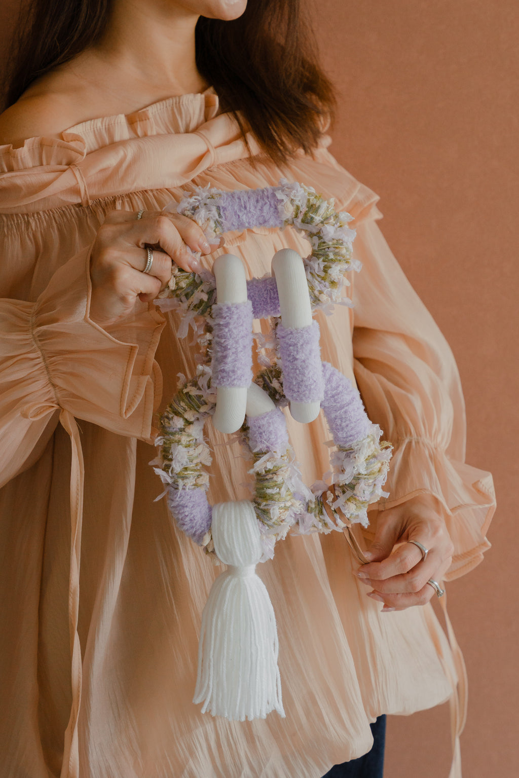 Close-up of Passing By Blooms Valley Wisteria: layered yarn in wisteria tones with interlaced leather, capturing delicate botanical texture.