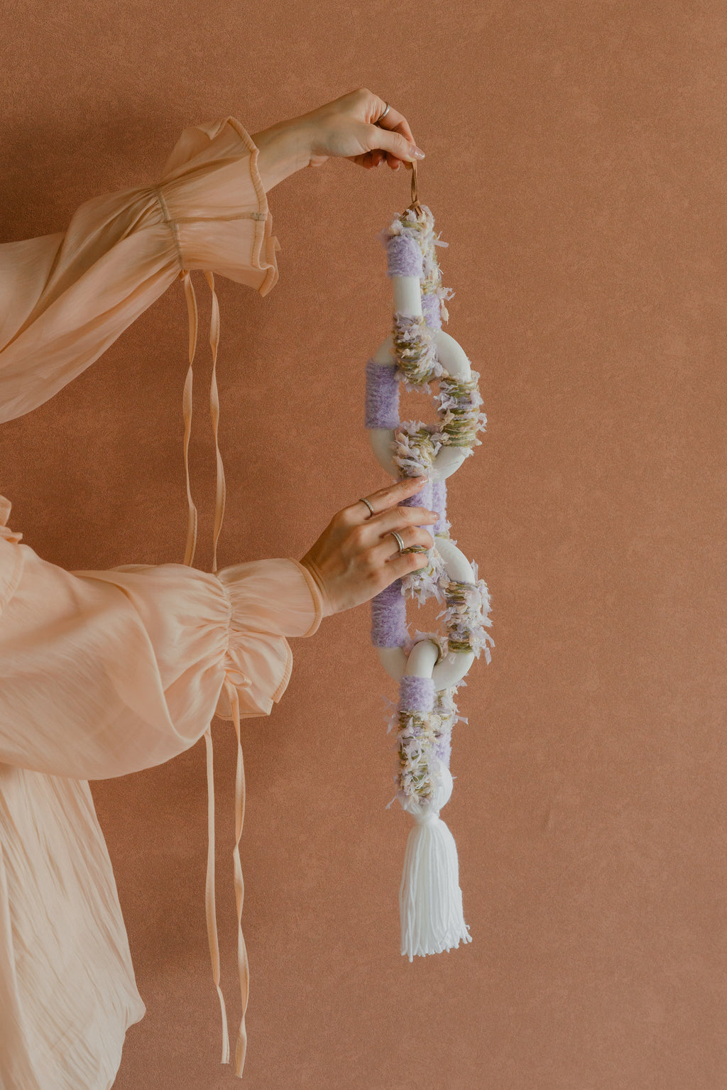 Passing By Blooms Valley Wisteria fibre wall art — soft lavender and dusty blue yarn woven into a cascading floral-inspired tapestry with leather accents.