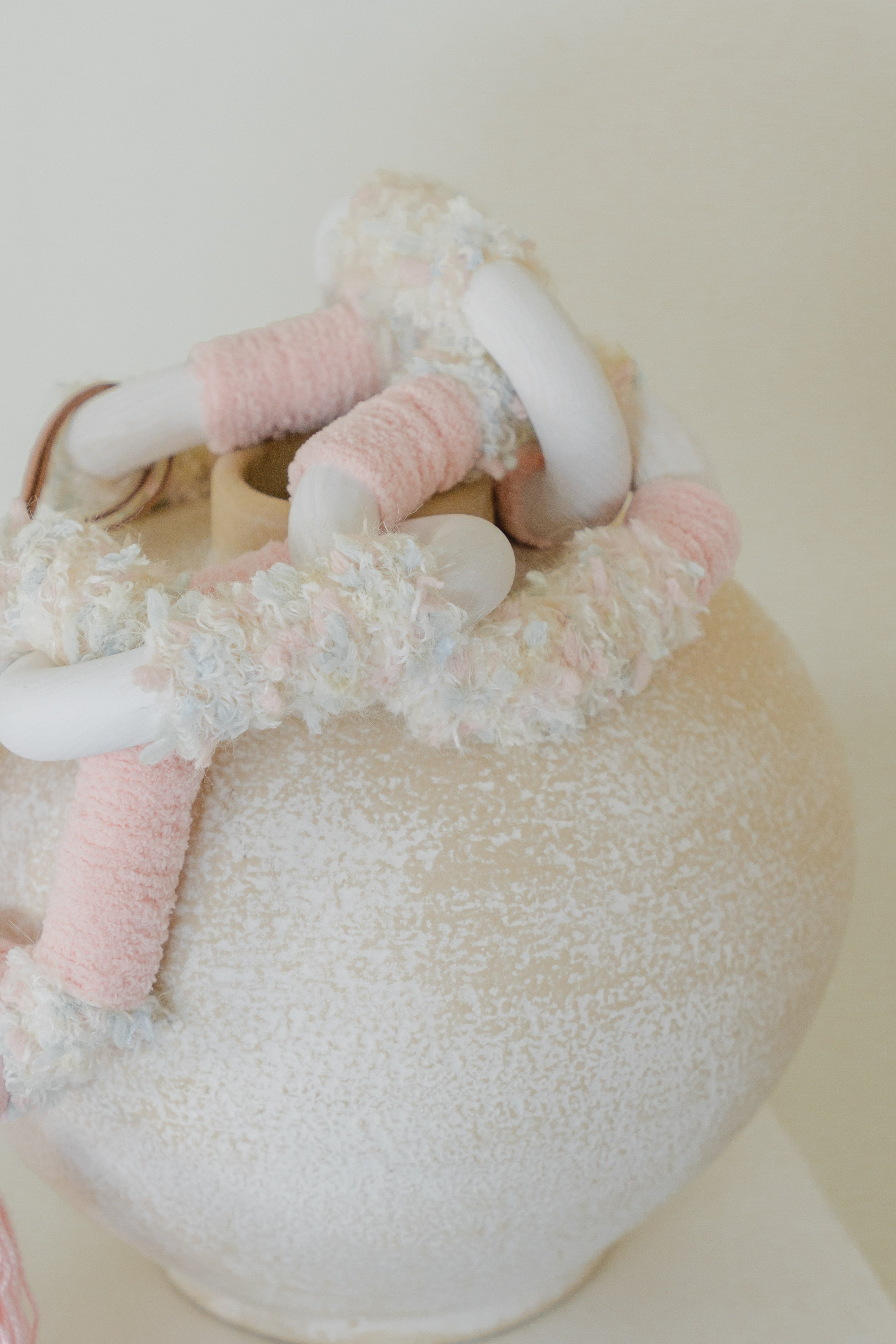 Detail of the Passing By Blooms Rose fibre art — blush-hued yarn in layers that softly mimic petals of a blooming flower.