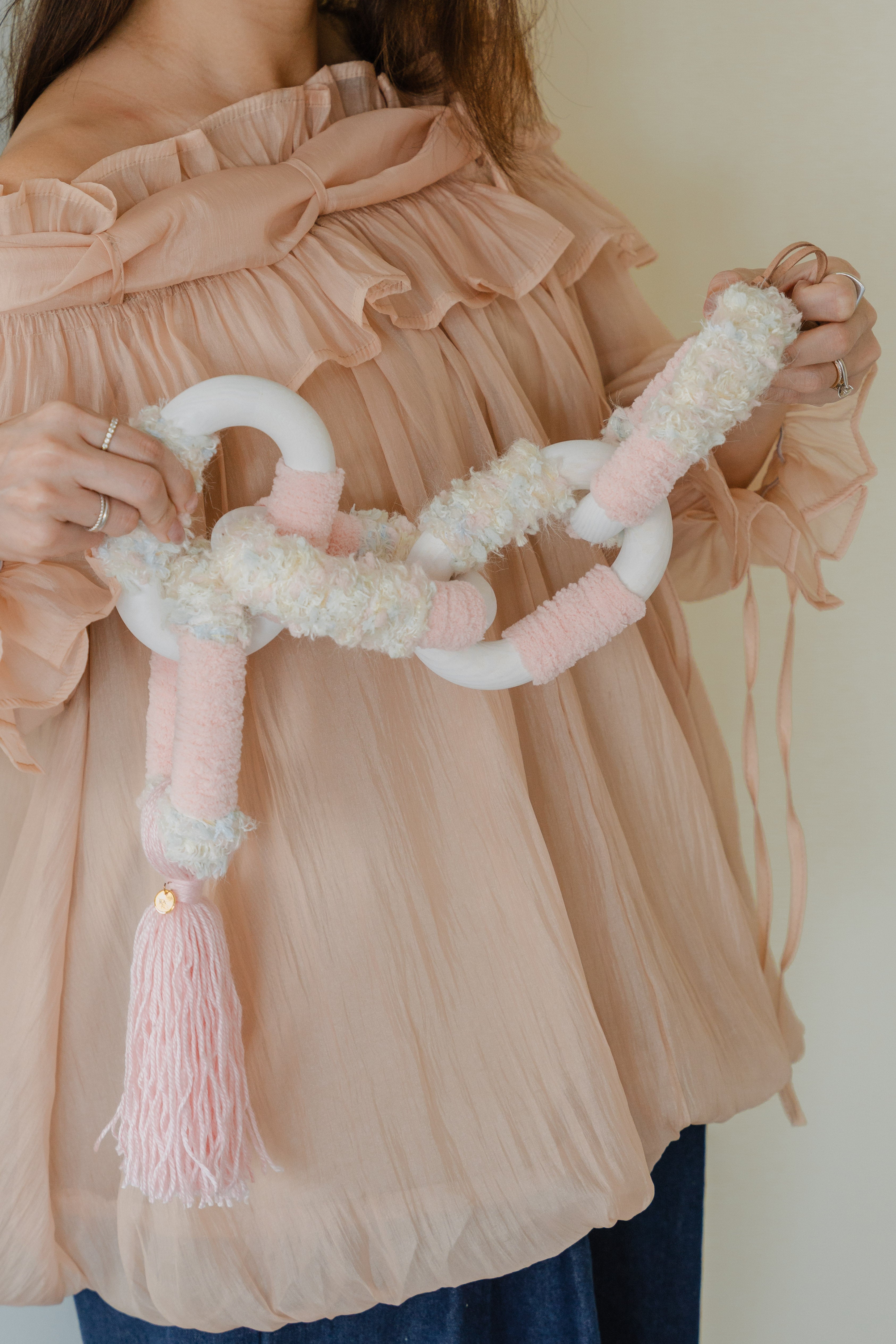 Close-up of Passing By Blooms Rose: layered blush yarn and hand-stitched leather forming delicate floral textures.