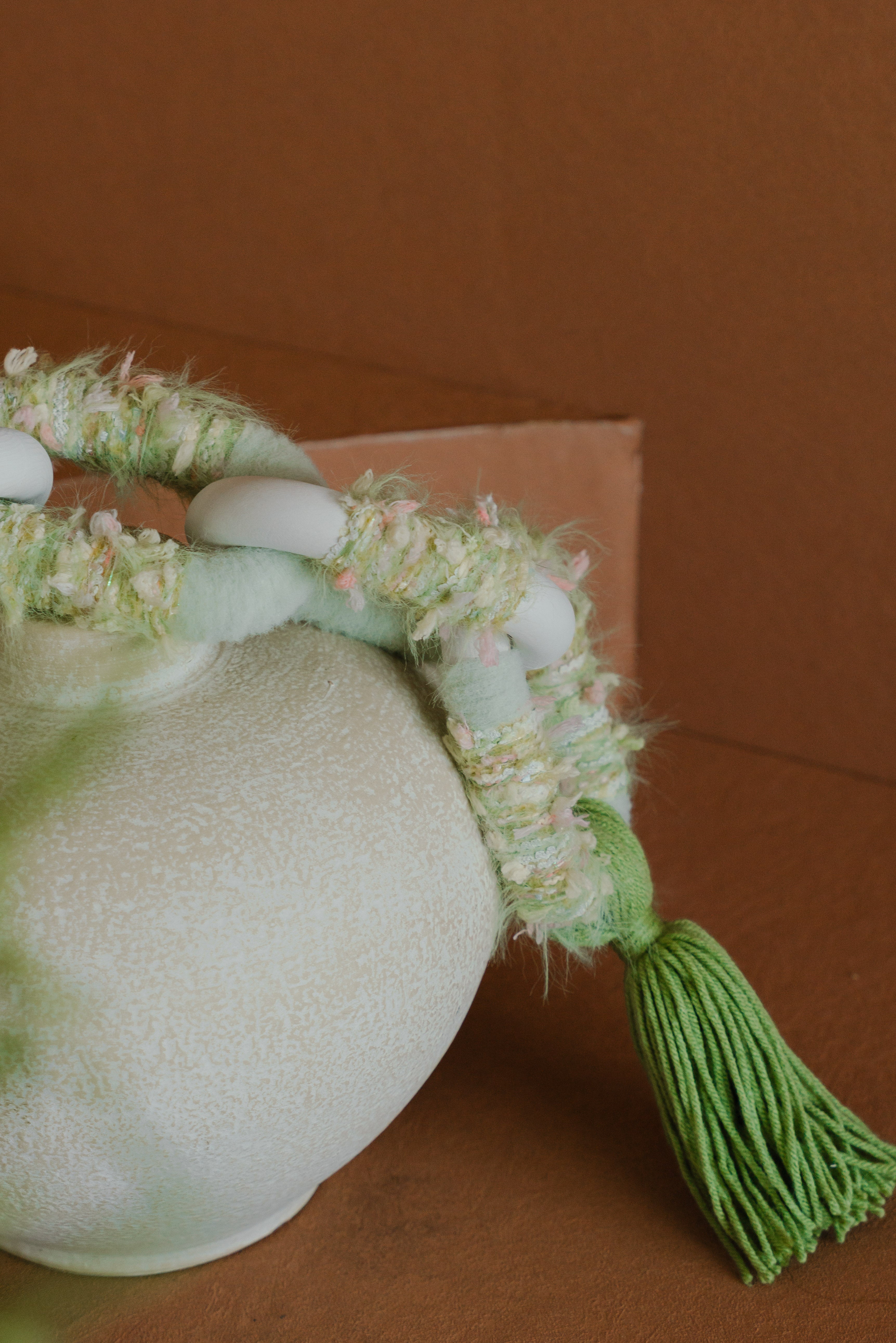 Angled view of the Valley fibre tapestry: layers of green yarn tumble softly downward, reminiscent of a lush valley in bloom.