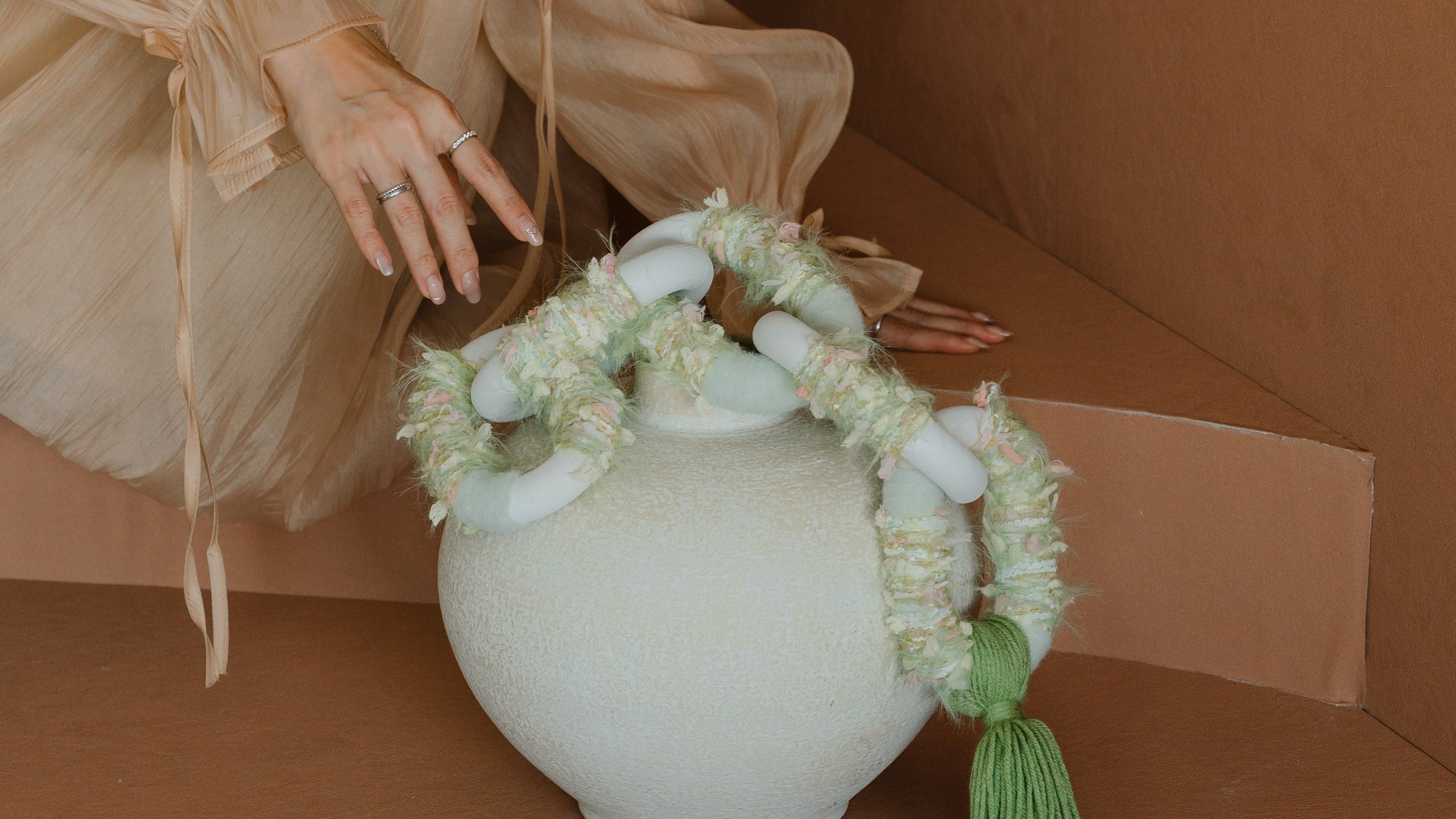 Passing By Blooms Valley setting against pale background, its soft green and cream weave adding natural warmth to a calm interior setting.