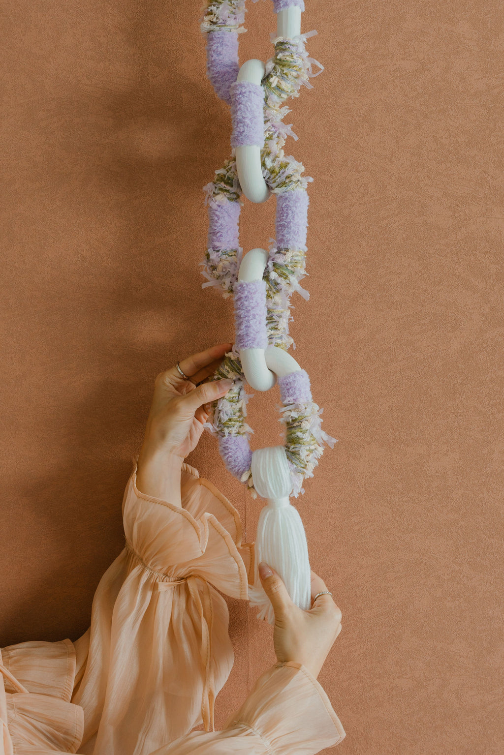 Detail of Passing By Blooms Valley Wisteria’s hand-stitched leather trims intertwined with pastel yarn, giving the piece refined structure and warmth.