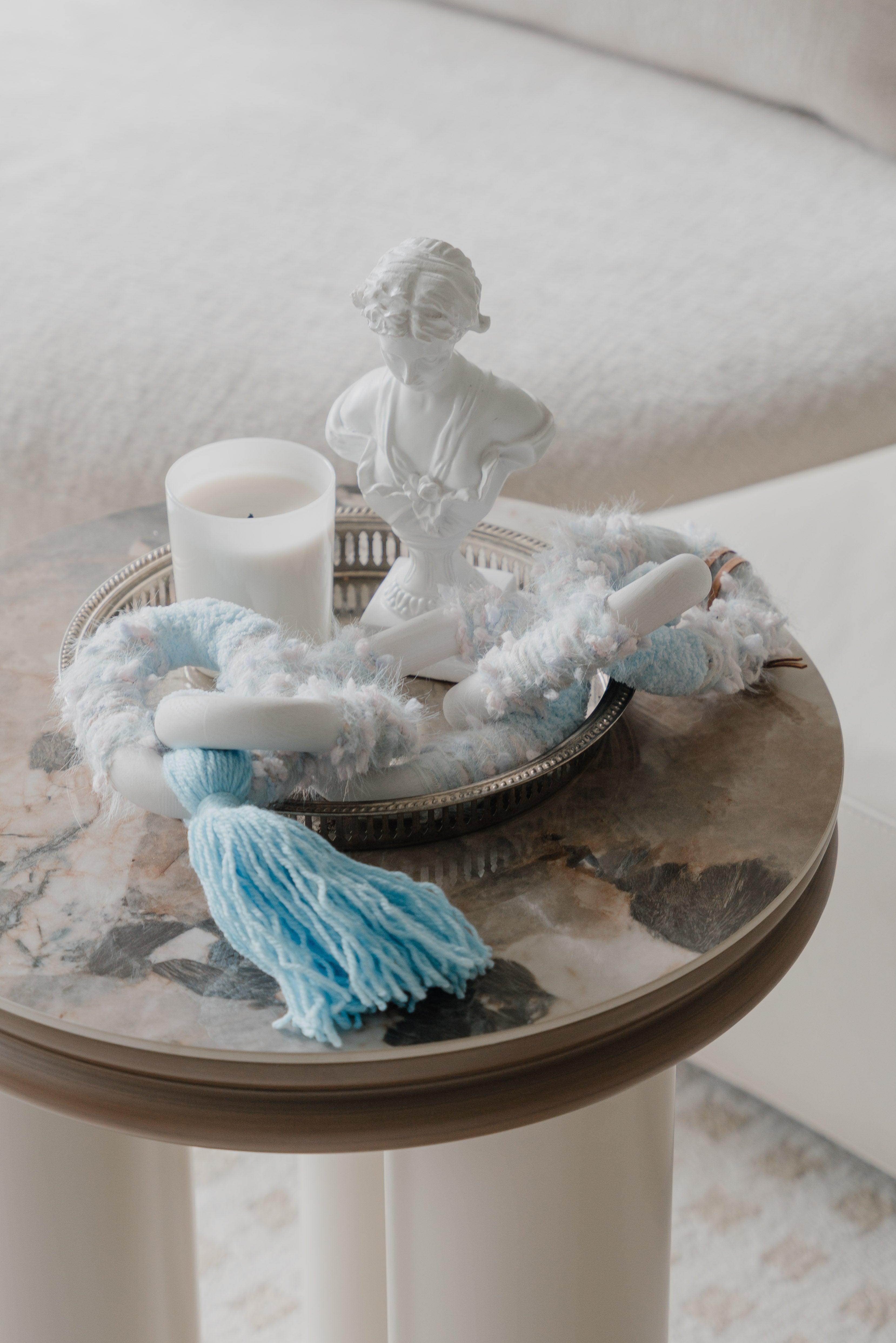 Passing By Blooms Delphinium fibre wall art — delicate yarn in lavender and periwinkle tones woven with leather accents, evoking drifting spring blossoms.