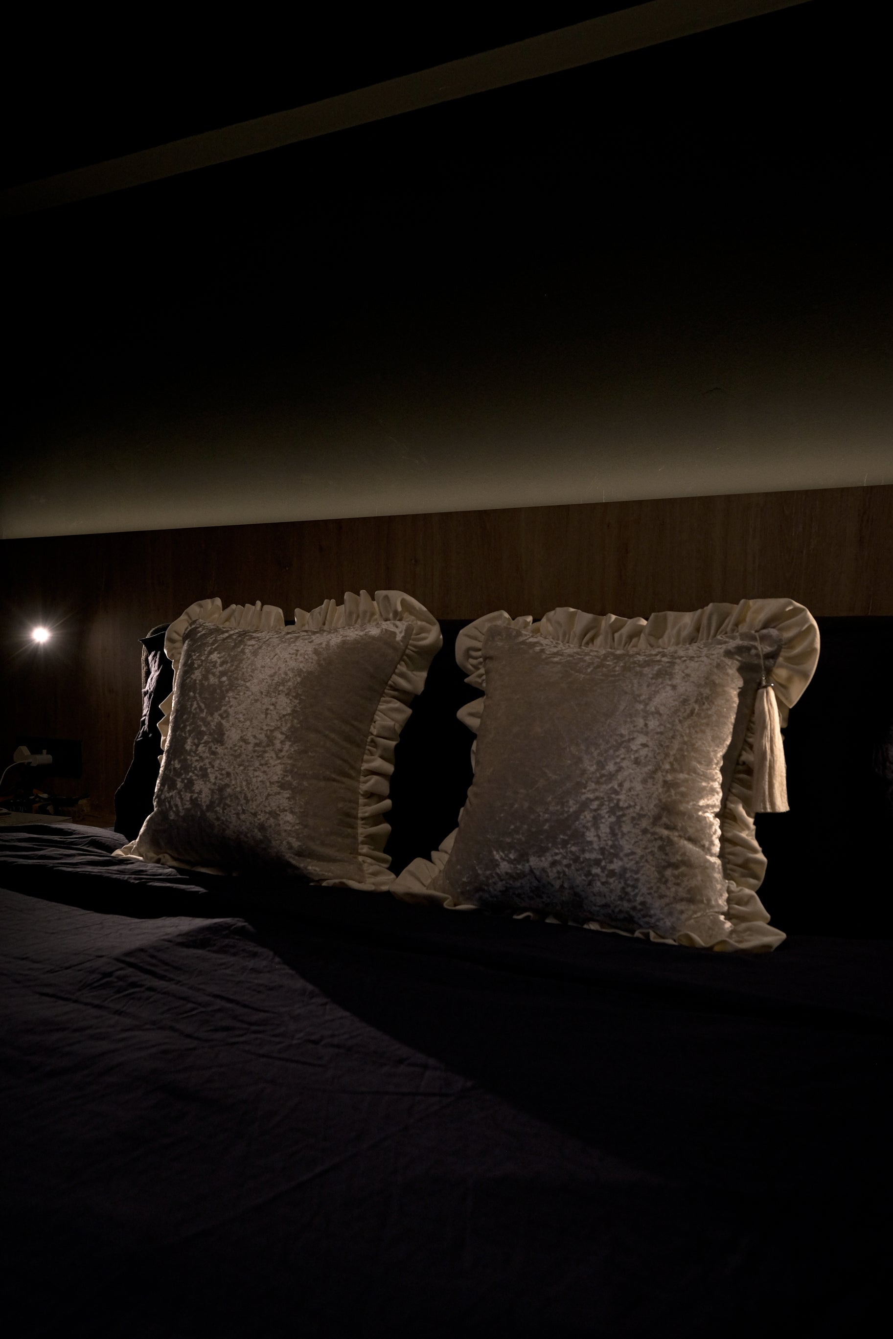 Cream scented throw cushion leaning against headboard — elegant bedroom accent.