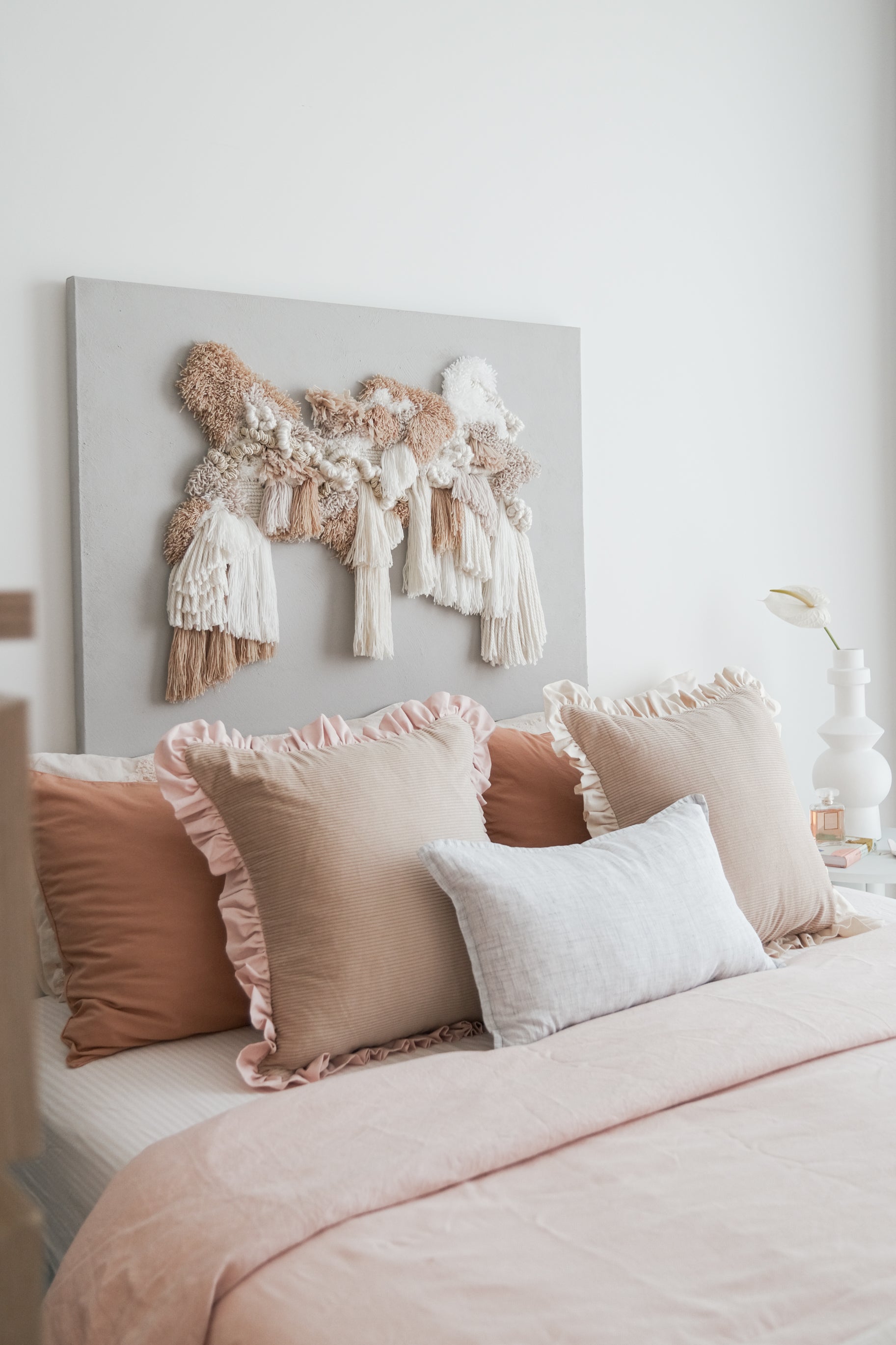 Kind Words Rosewater Cushion styled with neutral pillows — subtle color pop in bedroom.