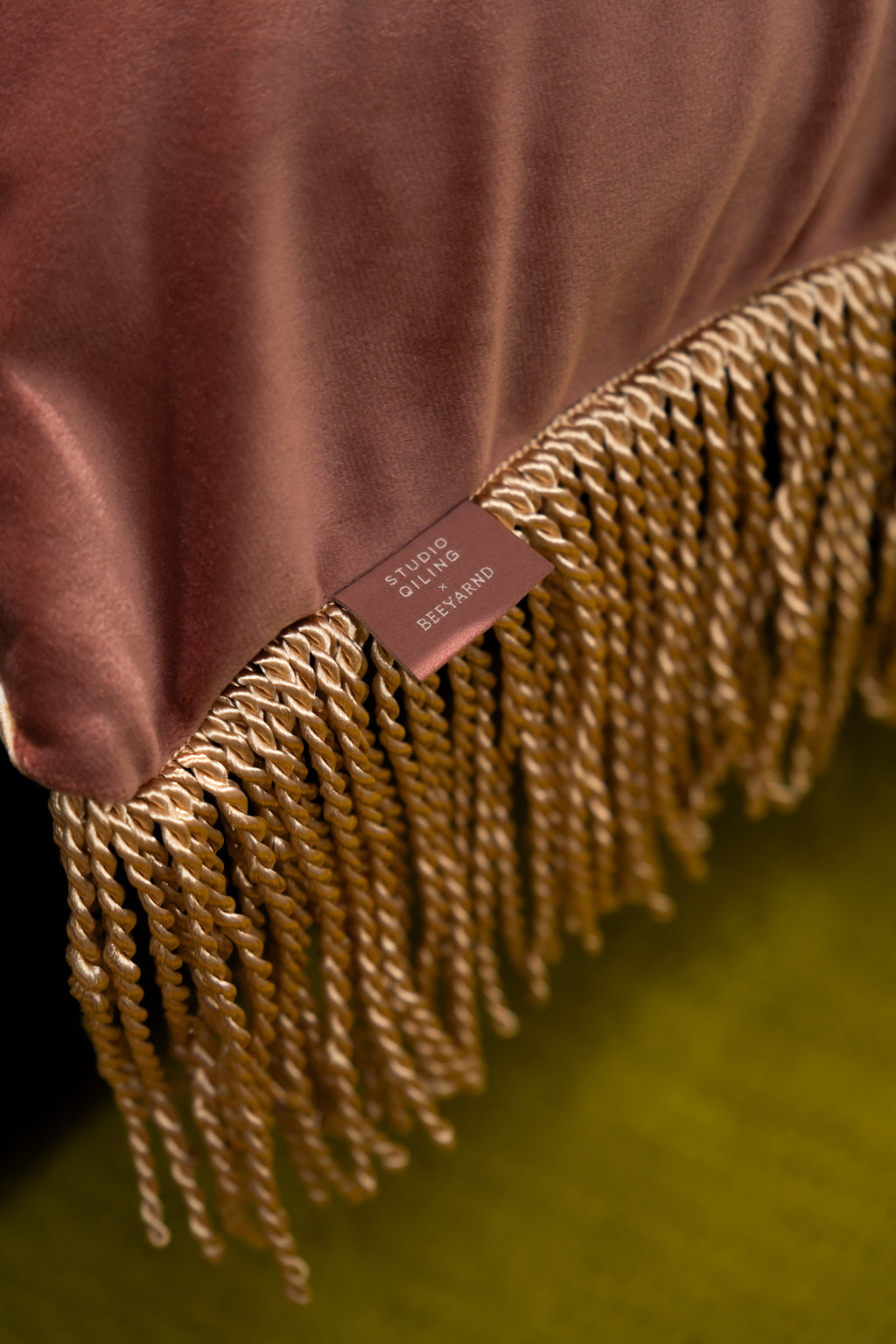 Detail of Dragon Dreams cushion: printed dragon motif in gold thread, smooth front fabric, rich velvet back, and corner tassels.