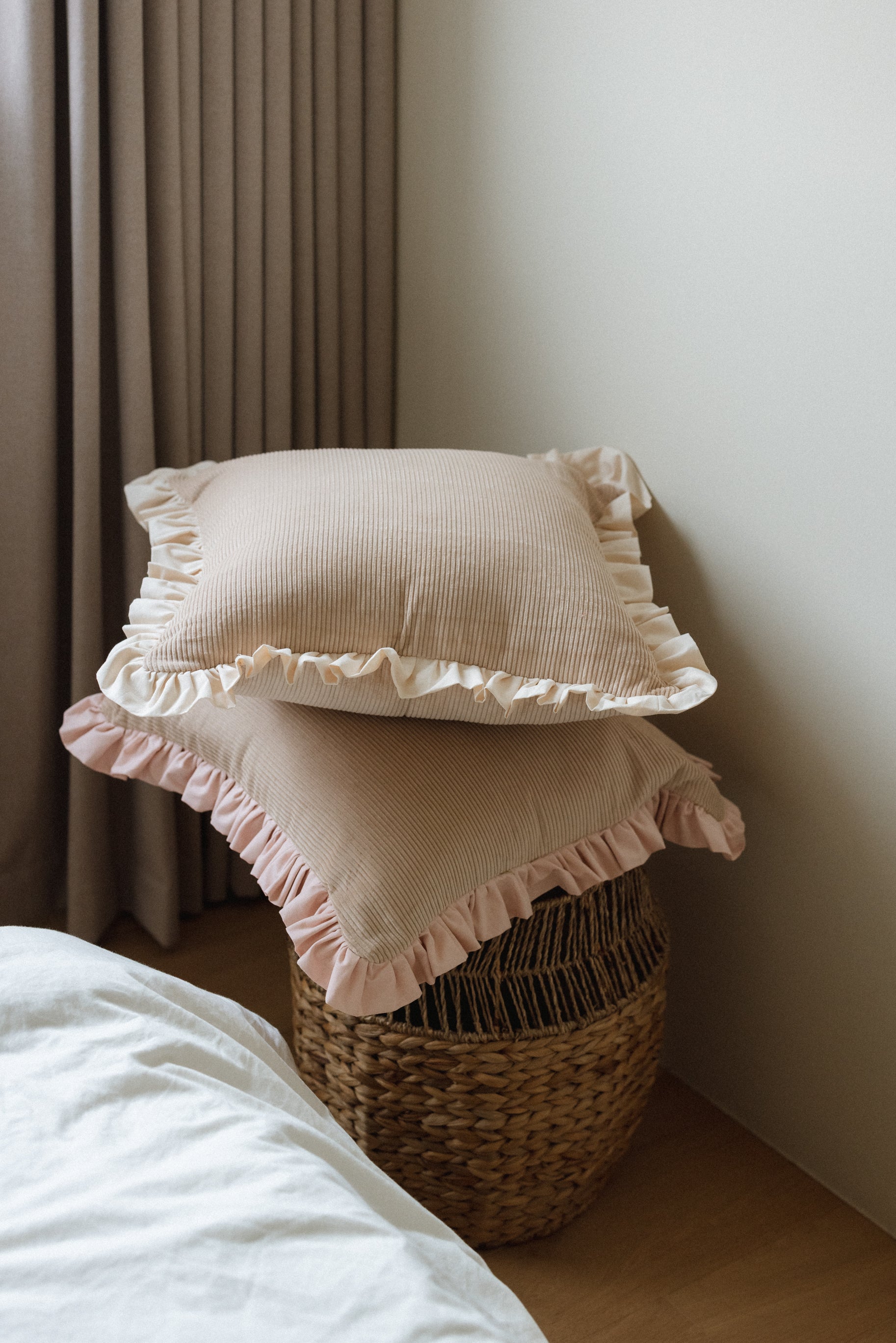 Kind Words Rosewater Cushion adding softness and stored on a wicker basket. 