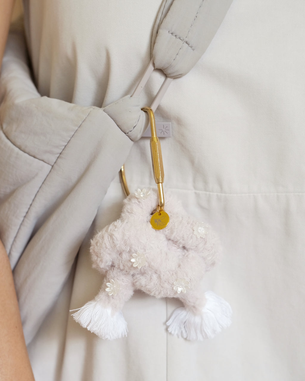 Wolf Ethereal keychain accessory hanging from a handbag, featuring a cuddly plush wolf and shiny gold clasp.