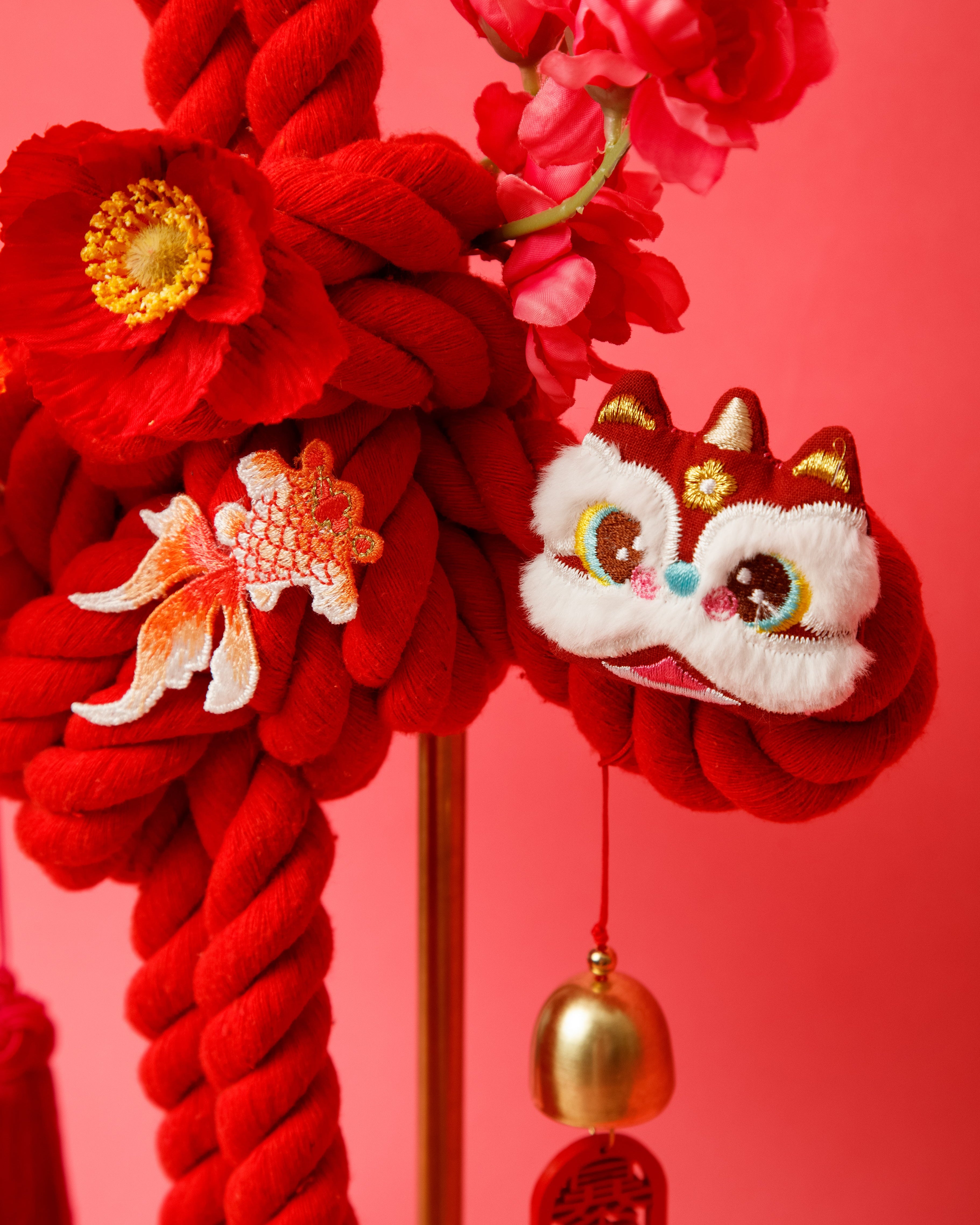 Intricately hand-woven red cord forming a traditional Wan knot with a delicate floral center. 精心手编的红绳制成的传统万字结，中心饰有精致花卉。