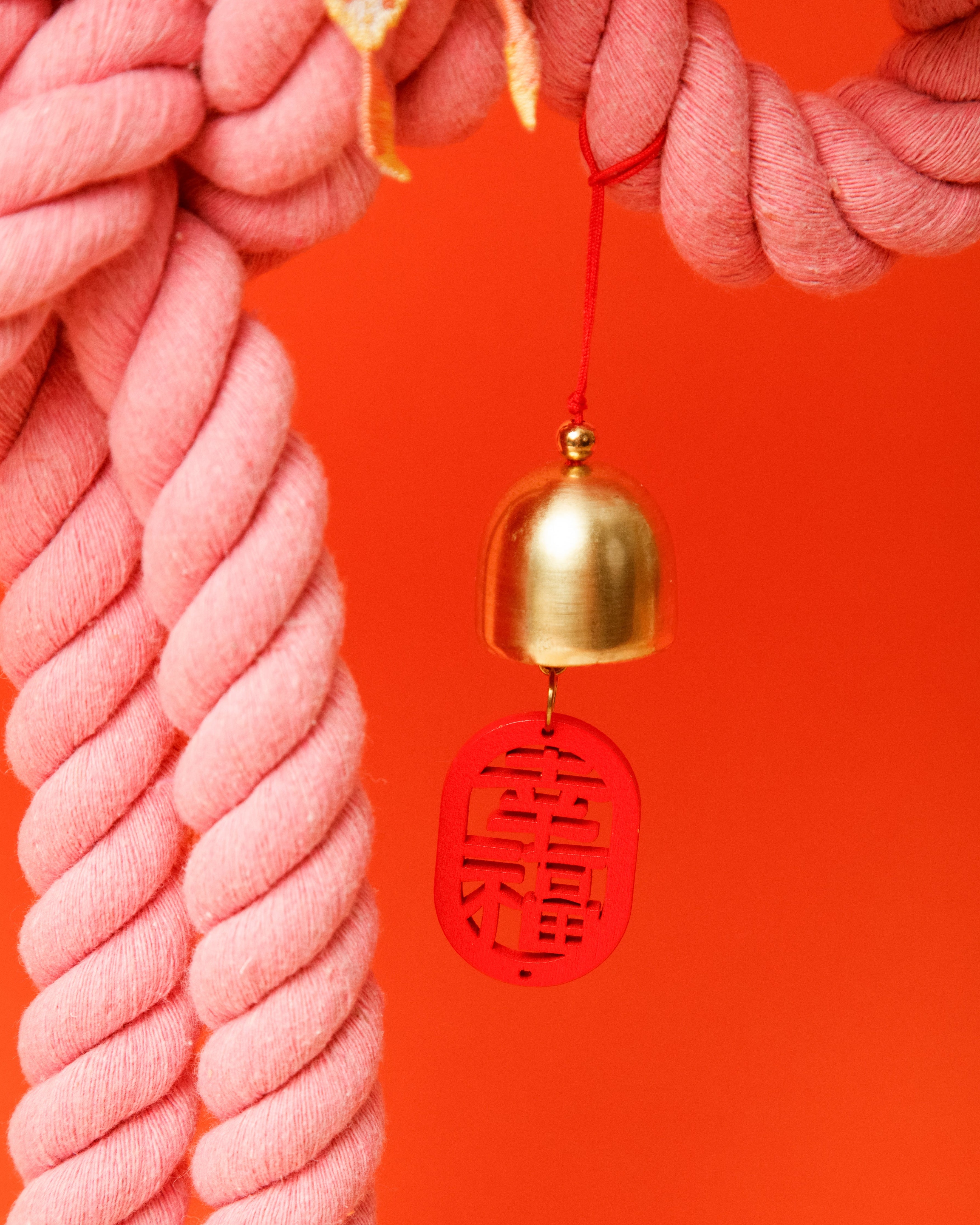 The Rose Reverie Wan Knot decoration, featuring embroidered details and a small jingle bell charm.